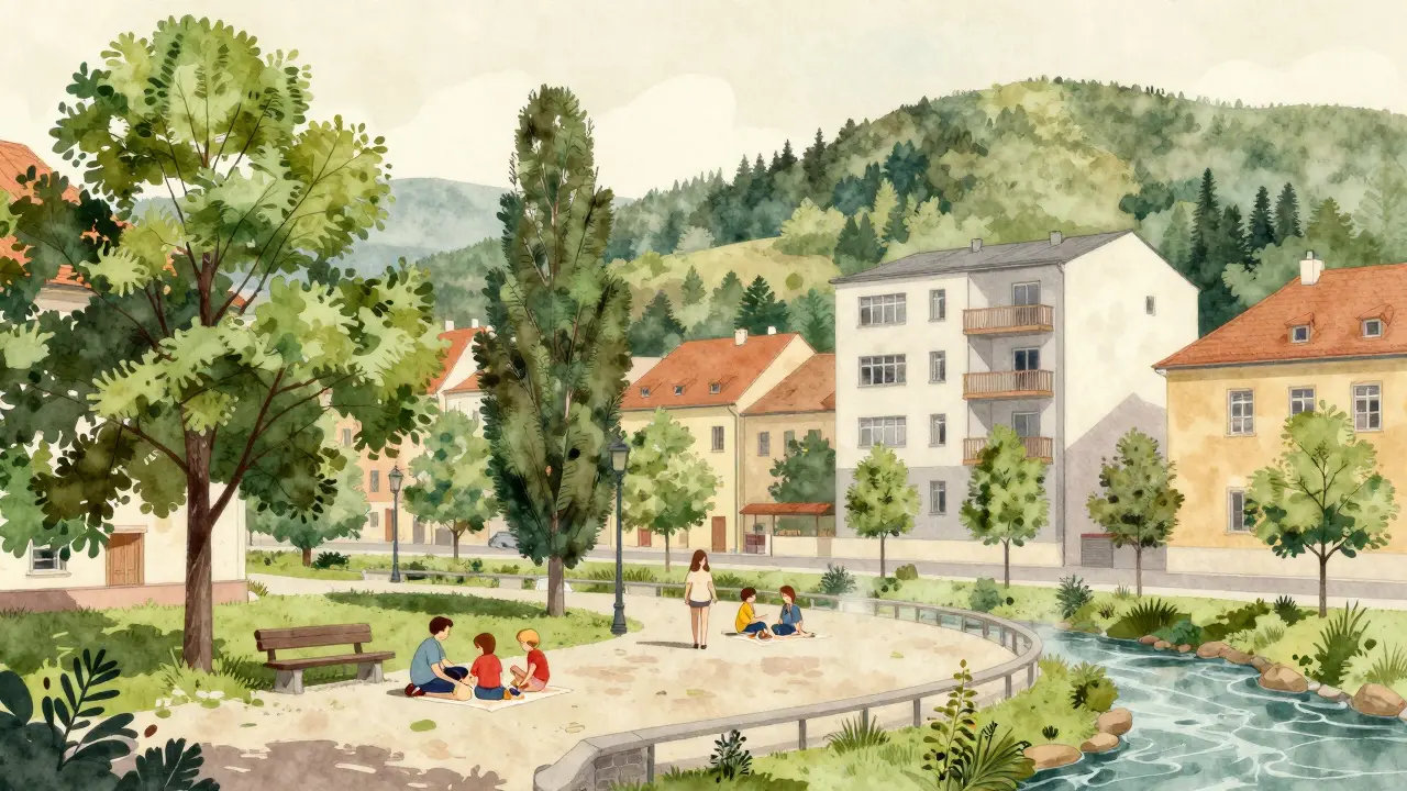 Malý park v Brně s vysokými stromy a rodinou na lavičce, s lesními výšinami na pozadí.