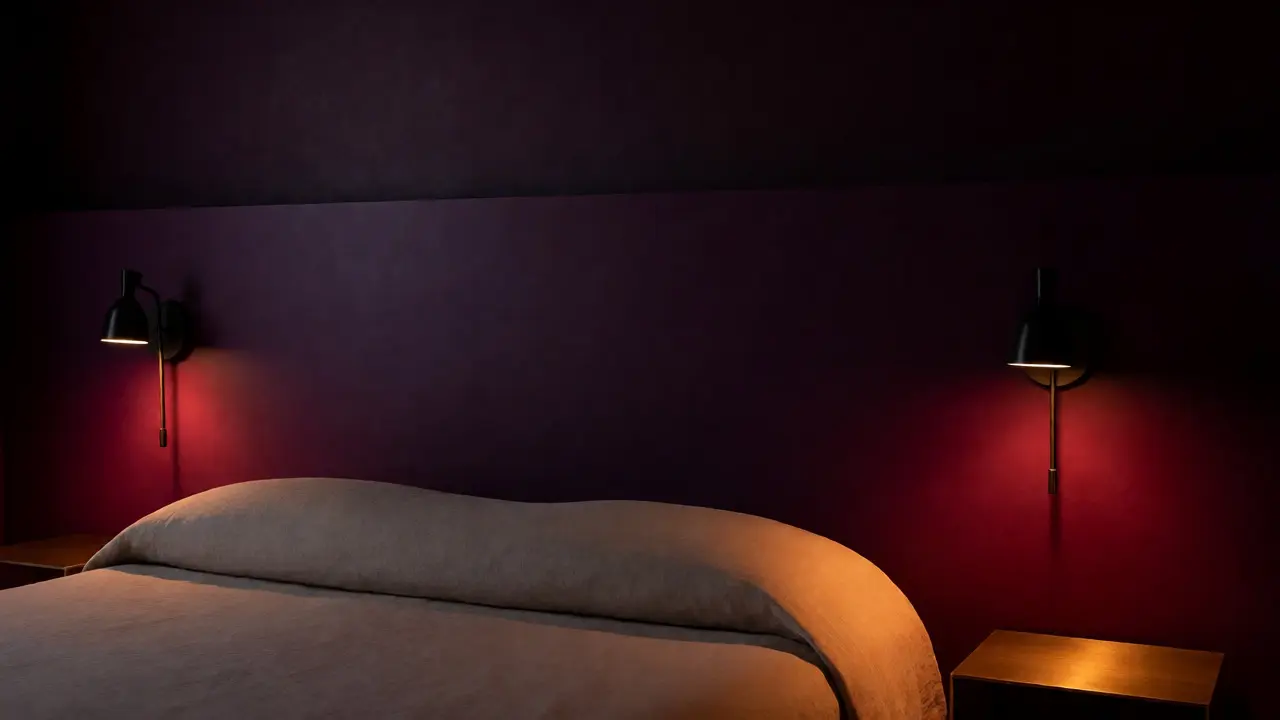 Ložnice ve večerním osvětlení s tmavě fialovou stěnou za postelí pro relaxaci